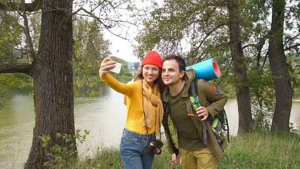 Beautiful Couple in Tourist Clothes Are Photographed in Autumn Forest.