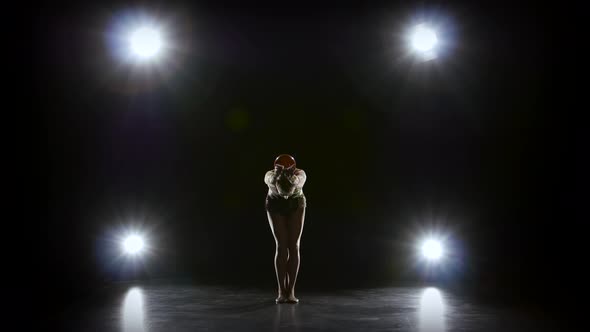 Flexible Gymnast Leads the Ball on His Body. Black Background. Light Rear