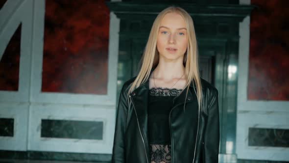 fashion portrait of a beautiful young woman with blue eyes and blonde hair in a leather jacket indoo