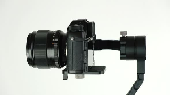 Electronic steadycam with digital camera rotates on white background.