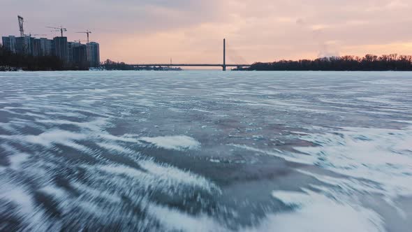 Drone Flying Above Frozen River to City Bridge Close Up