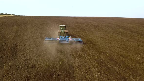 Aerial footage of a tractor plowing black agriculture farm field after harvesting in autumn.