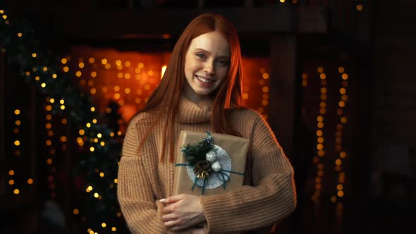 Portrait of Young Beautiful Woman Holding Box with Christmas Presents Wrapped in Craft Paper.