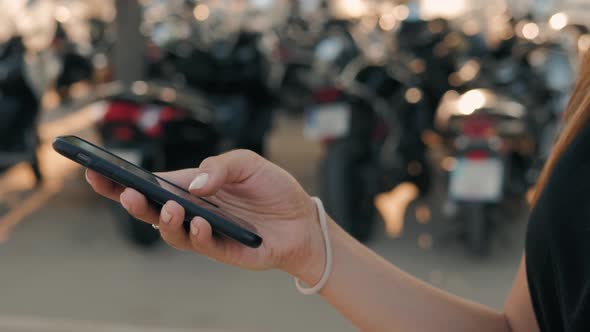 Woman Checking Smart Phone Showing Screen on Scooter Parking. Motorbiker on Her Motorbike Checking