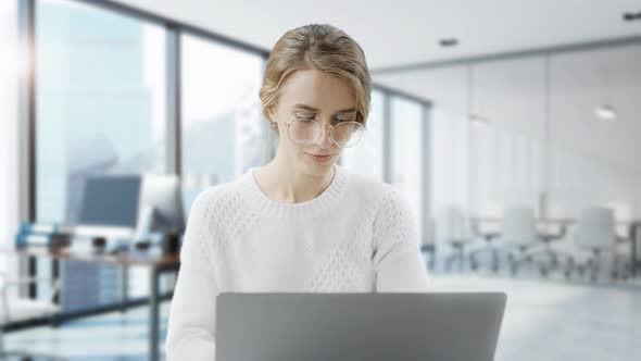 Woman Is Using Laptop While Sitting at Her Desk. Young European Businesswoman Is Sitting in the