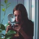 Woman photographer taking a picture of a plant, window reflection - VideoHive Item for Sale