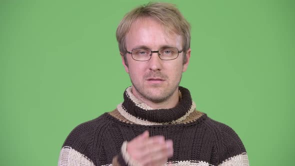 Studio Shot of Blonde Handsome Man Covering Mouth As Three Wise Monkeys Concept