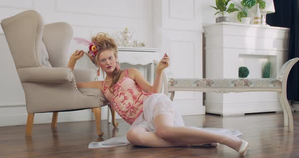 18Th Century Woman is Sitting on the Floor with a Feather in Hand Posing