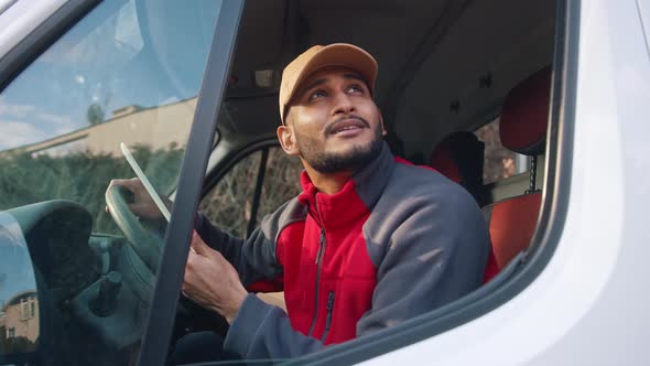 Delivery Driver Looking at Tablet and Then Outside to Confirm Delivery Address