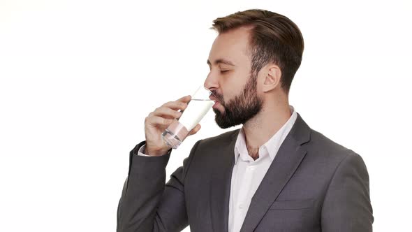 Horizontal Portrait of Pleased Glad Guy Wearing Office Suit Drinking Mineral Water From Transparent