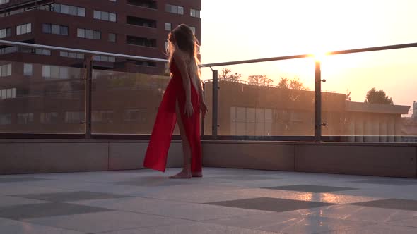 Beautiful Young Girl Dancing on the Street of a Modern City in the Sunset Light. She Is Wearing a