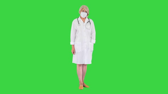 Senior Female Doctor During a Coronavirus Pandemic Covid19 Takes Off Protective Mask on a Green