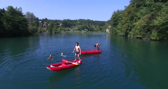 Friends doing backflip from canoe into river