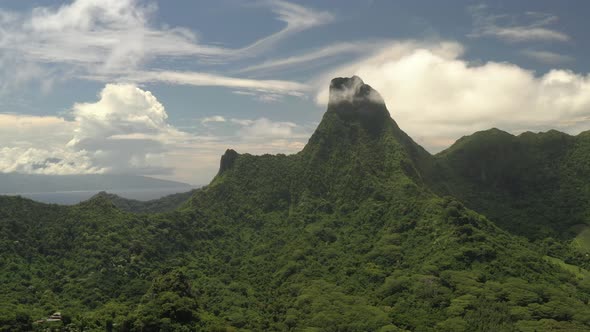 Aerial shot of a spectacular mountain covered by lush vegetation in Mo'orea island. Jib up