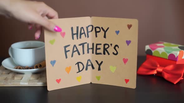 Girl Puts Greeting Card on a Table on Fathers Day