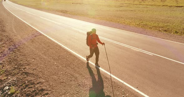 Flight Over Hitchhiker Tourist Walking on Asphalt Road. Huge Rural Valley at Summer Day. Backpack