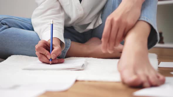 Student Girl Sits On The Floor With Bare Legs Writes Text On A Sheet Of Paper Diary. The Student