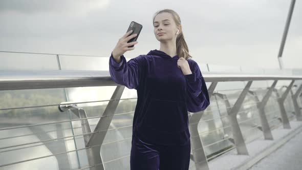 Portrait of Charming Young Caucasian Sportswoman Taking Selfies Outdoors