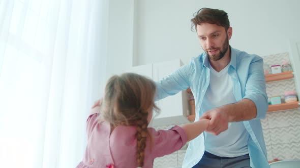 Dancing young father and little cute girl in the living room. Young family having fun