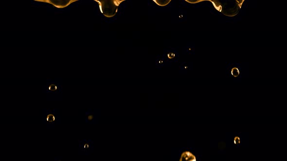 Super Slow Motion Shot of Falling Golden Droplets Isolated on Black Background at 1000 Fps