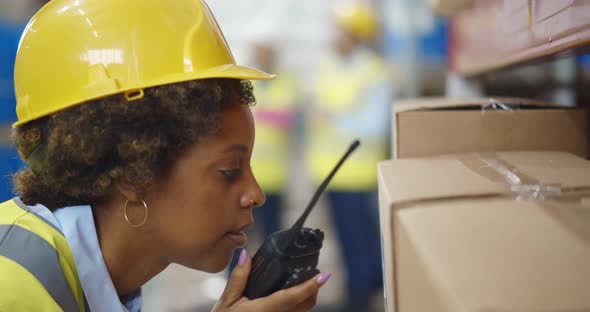 Professional Female Cargo Worker Talking on Portable Radio to Contact Another Worker