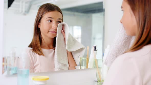 Teenage Girl Wiping Face with Towel at Bathroom