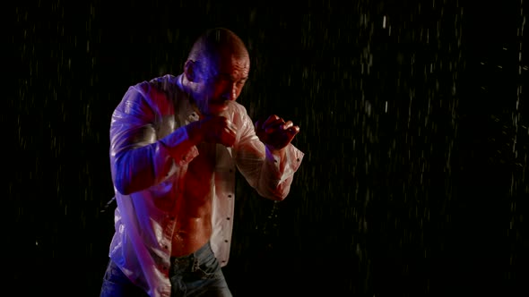a Man in an Unbuttoned White Shirt is Boxing in Streams of Water on a Dark Background