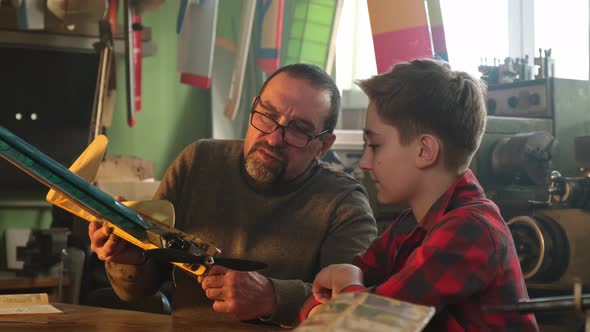 A Boy with a Teacher is Studying the Device of a Miniairplane Engine