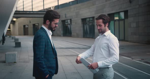 Cheerful Male Colleagues Discussing Successful Meeting with Business Partners Standing in Outdoor
