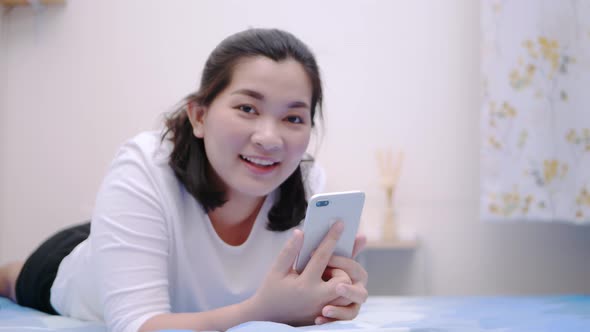 Thai asian woman looking and touching smartphone relax enjoy and smile with online social media in b