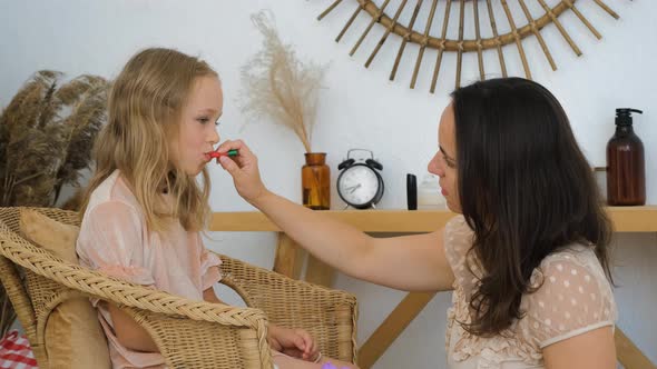 Mother Painting Lips of Her Cute Little Daughter