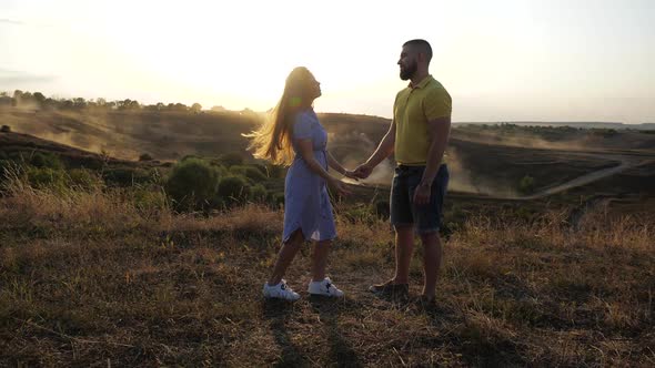 Side View of a Cute and Beautiful Couple in Love on the Field. A Nice Girl Slowly Approaches Her