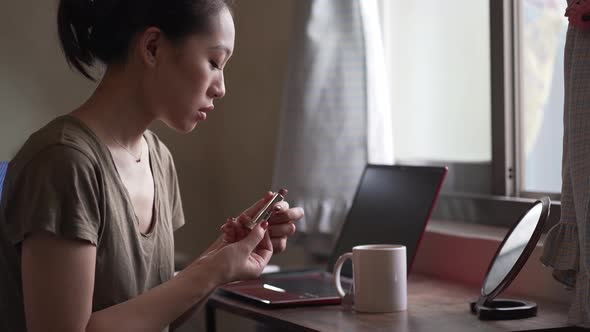 Asian woman painting lips with lipstick