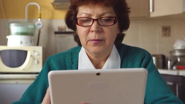 Portrait Of A Mature Woman With A Glasses Is Using A Tablet Pc At Home