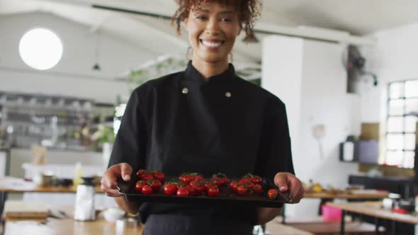 Mixed race female chef holding a plate with tomatoes