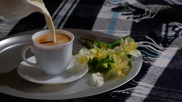 Pouring milk from milkman in white cup with hot coffee