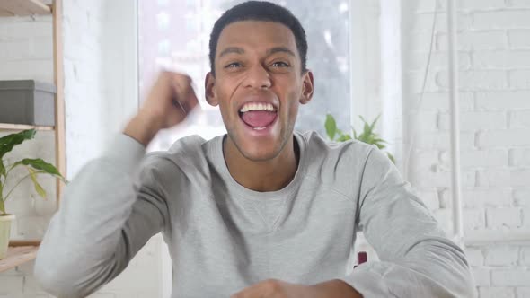 Happy AfroAmerican Man Celebrating Success Watching TV