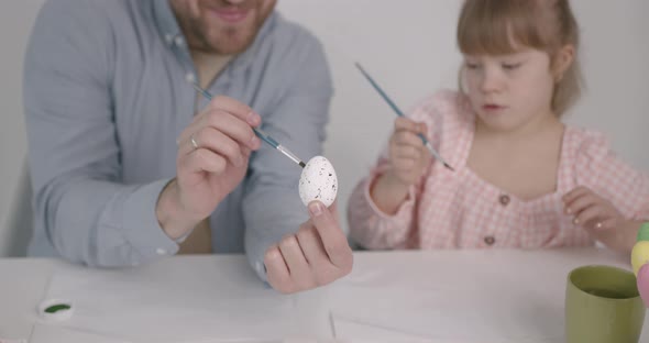 Girl with Down Syndrome Painting Easter Eggs with Father