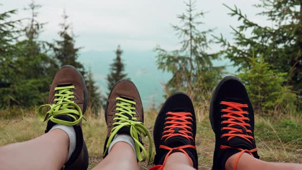 A Pair Of Hikers Dance With Their Feet In The Mountains In The Background. Close Up  Legs Of Hikers