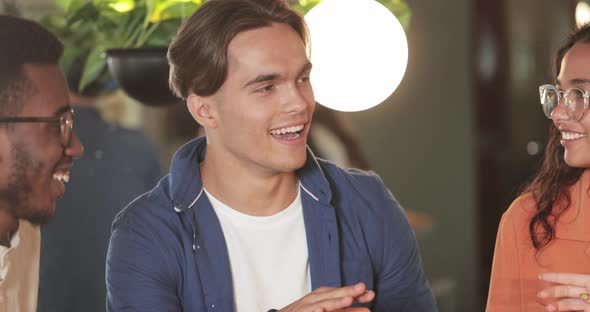 Milennial Handsome Guy Talking While Sharing Thoughts with Coworkers in Modern Cafe During Lunch