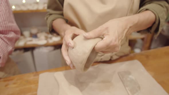 Hands of Unrecognizable Woman Smoothing Walls of Clay Bowl in Workshop