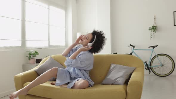 Excited Young Adult Woman Singing While Listening Music on Headphones at Home