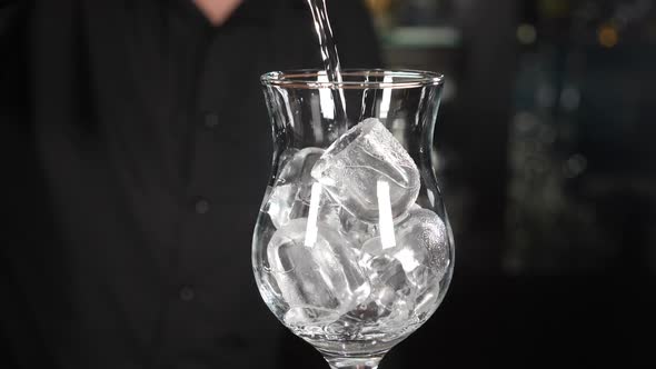 Bartender Making Cocktail Pouring Transparent Alcohol Liquid Into Glass with Ice Cubes