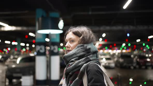 Young Woman Walks Along Blurry Parking Lot in Cold Evening