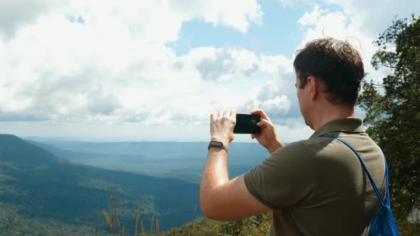 Blogger or Vlogger Recording Video on Smartphone Standing on High Mountain Top