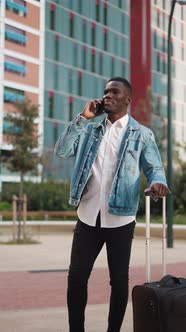 Content Black Traveling Man with Suitcase Talking on Smartphone