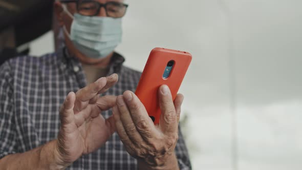 Senior Man in Face Mask Scrolling on Smartphone in Bus