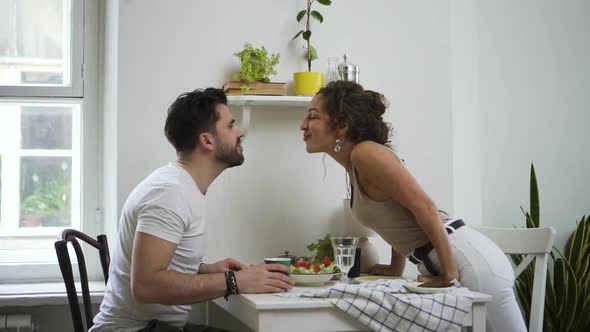 Young American Husband and Wife are Kissing During Dinner at Table in Home Kitchen Spbd