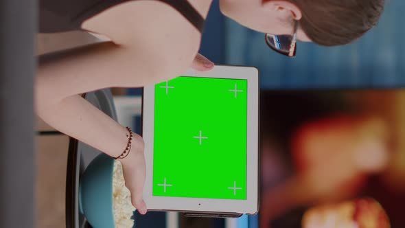 Back View of Young Woman Holding Digital Tablet with Green Screen Watching Social Media Video