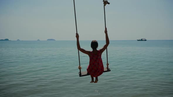a Woman on a Swing Over the Sea
